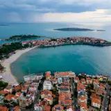 Malownicze wybrzeże podczas wycieczki do Bułgarii. Widok z lotu ptaka na miasteczko z czerwonymi dachami, plażę i turkusowe morze.