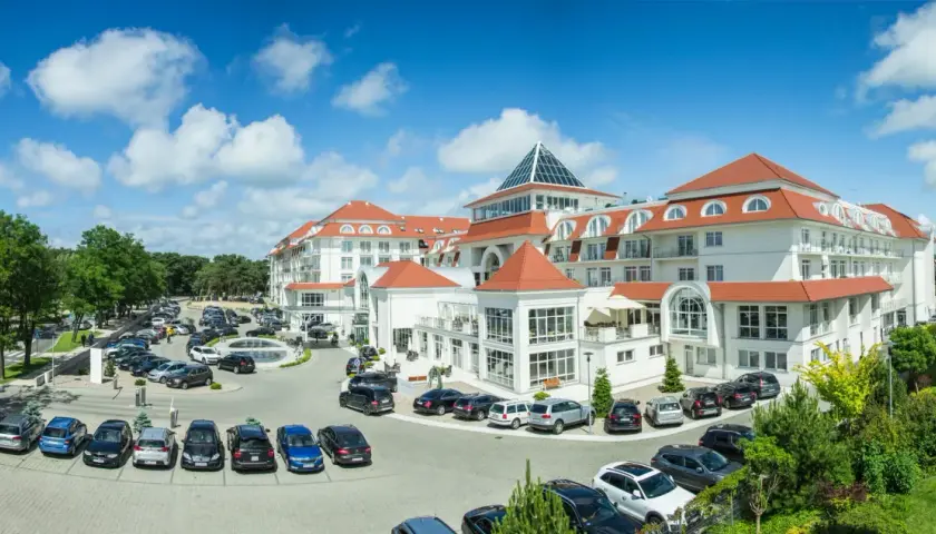 Elegancki hotel 5 gwiazdkowy nad morzem z dużym parkingiem i zielonym otoczeniem.