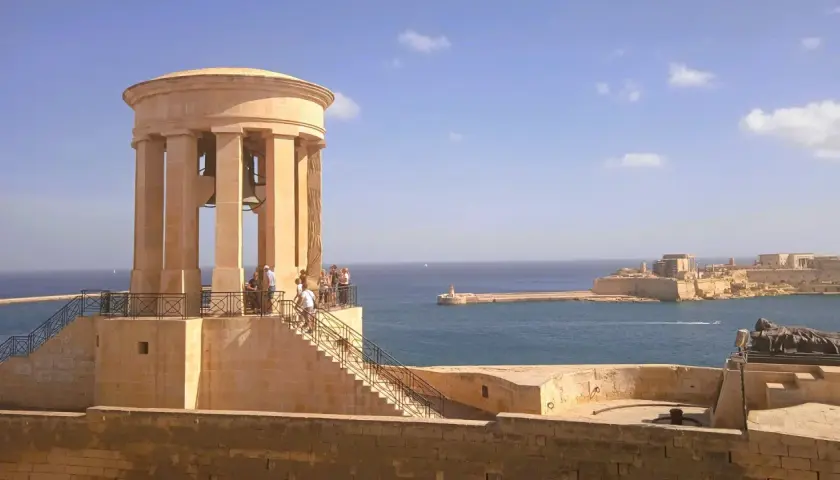 Malta, kwiecień: słoneczna pogoda nad portem, widok na zabytkową wieżę z dzwonami i fortyfikacje.