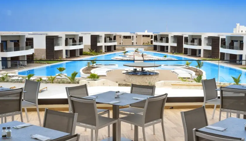 Luksusowy resort Royal Horizon Ponta Sino z basenem i barem. Stoły na tarasie czekają na gości.
