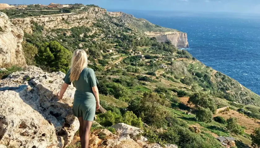 Malta w listopadzie: kobieta podziwia malownicze klify i morze. Pogoda sprzyja spacerom po zielonych wzgórzach.