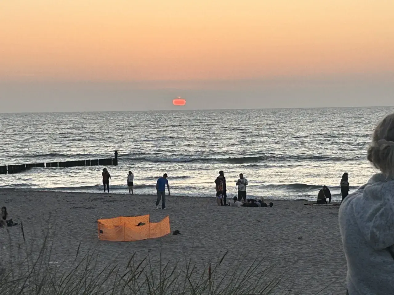 Zachód słońca nad morzem w Mielnie. Ludzie spacerują po plaży, zastanawiając się, ile mieszkańców ma Mielno.